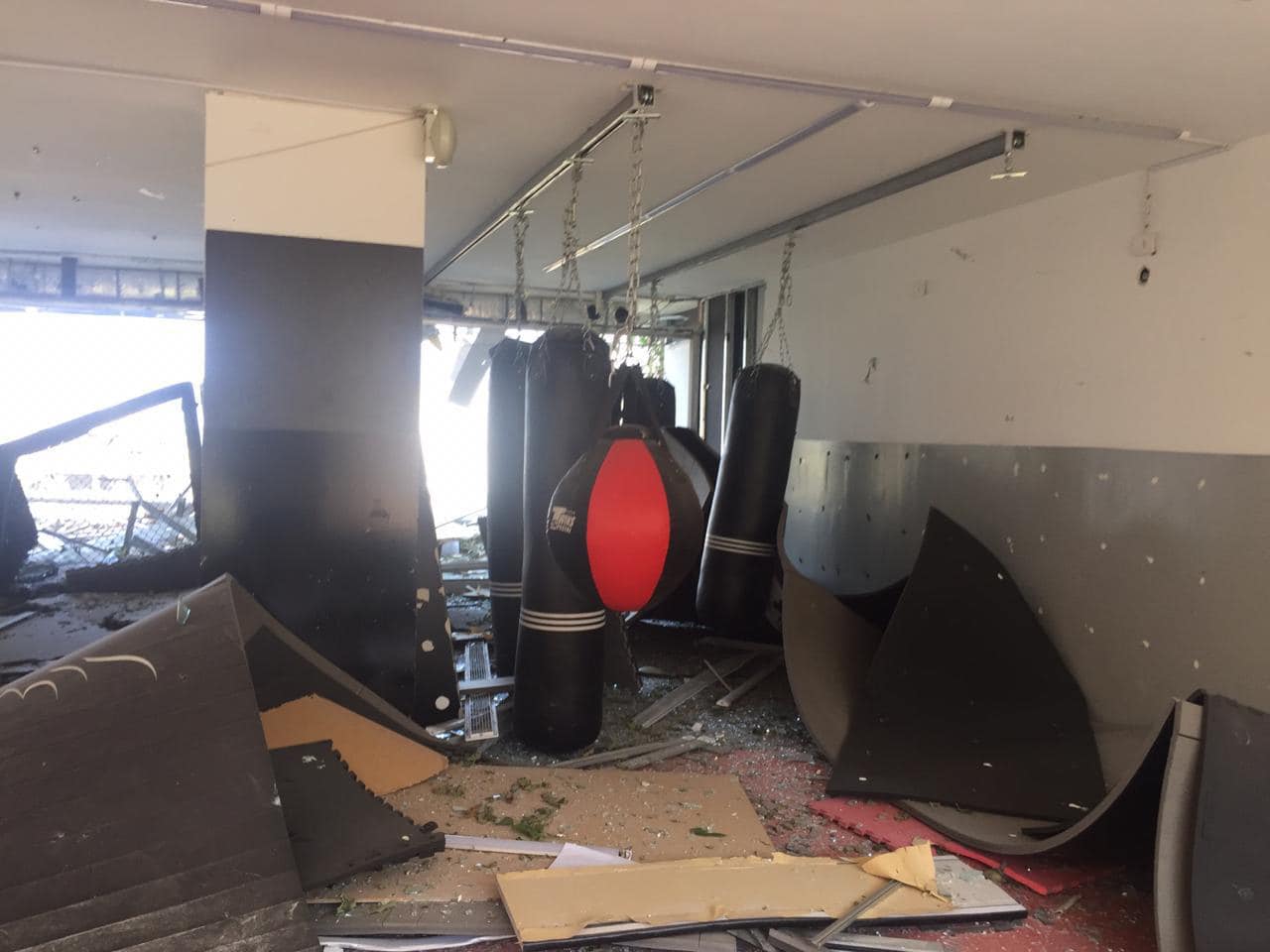 Punching bags left hanging amid debris and broken glass